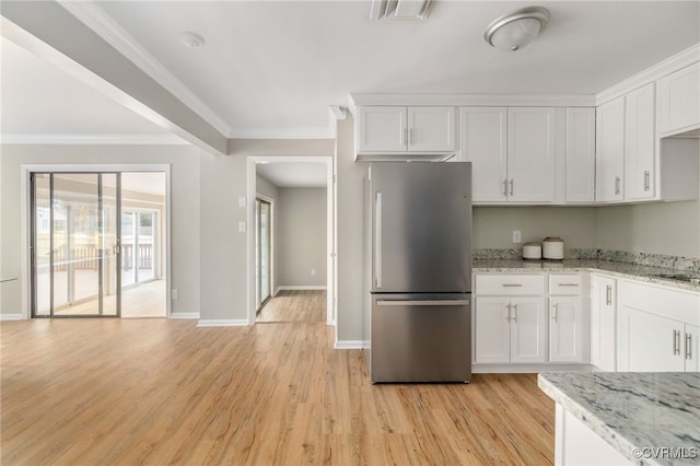 kitchen featuring stainless steel refrigerator, light wood-type flooring, light stone counters, and white cabinetry