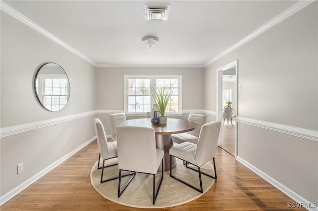 dining space featuring crown molding and light hardwood / wood-style flooring