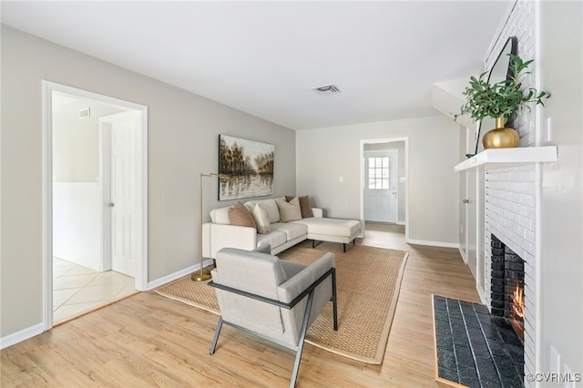 living room featuring a brick fireplace and light hardwood / wood-style floors