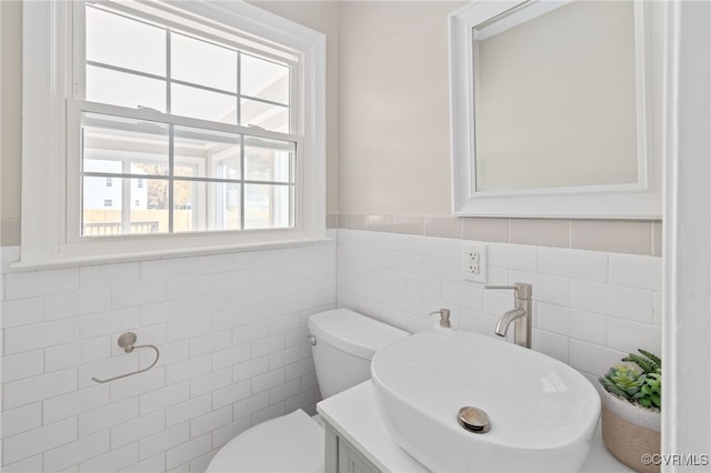 bathroom with toilet, vanity, and tile walls