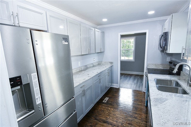 kitchen with light stone countertops, ornamental molding, stainless steel appliances, and dark wood-type flooring