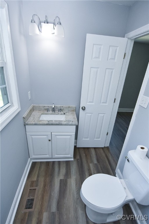 bathroom with hardwood / wood-style floors, vanity, and toilet