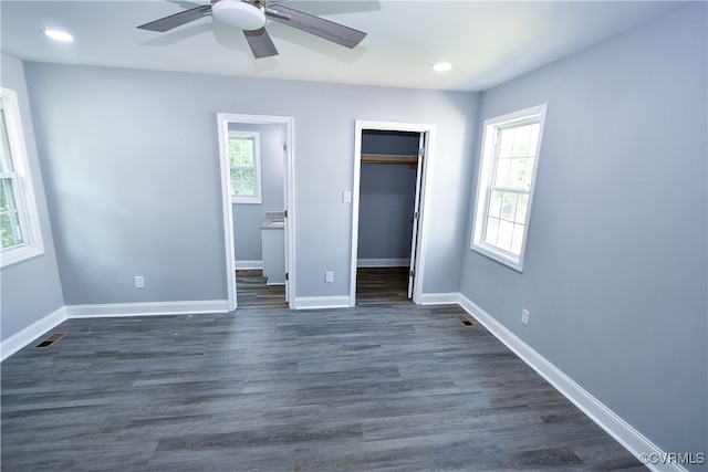 unfurnished bedroom featuring a walk in closet, ceiling fan, and dark hardwood / wood-style floors