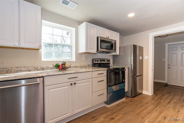 kitchen featuring light hardwood / wood-style floors, light stone counters, white cabinetry, and stainless steel appliances