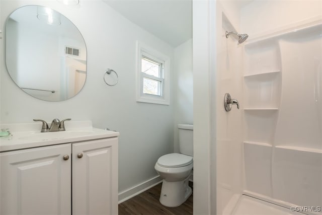 bathroom with hardwood / wood-style flooring, toilet, walk in shower, and vanity