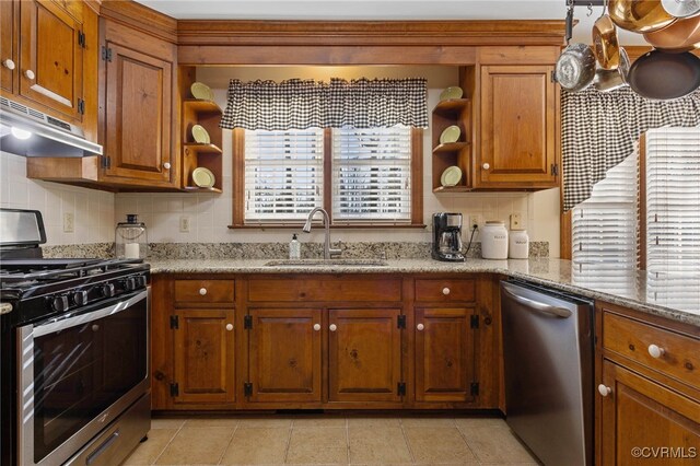 kitchen featuring tasteful backsplash, light stone countertops, sink, and stainless steel appliances