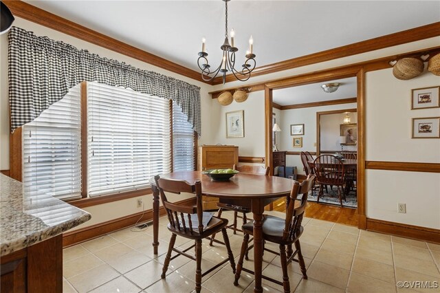 tiled dining space featuring an inviting chandelier and ornamental molding