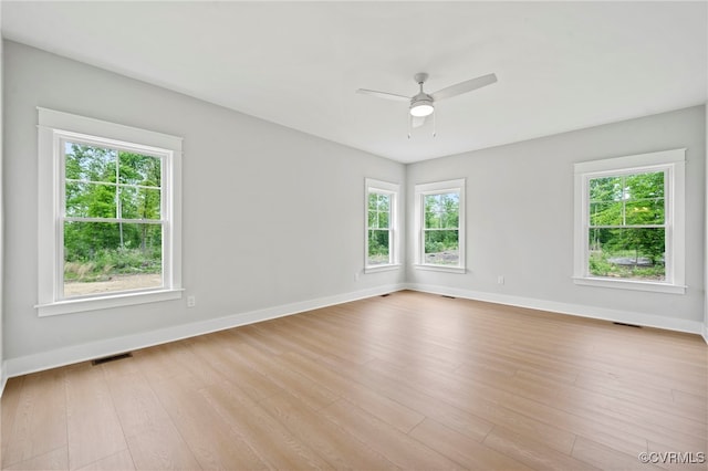 spare room featuring plenty of natural light, ceiling fan, and light hardwood / wood-style flooring