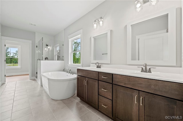 bathroom with tile patterned floors, vanity, and shower with separate bathtub