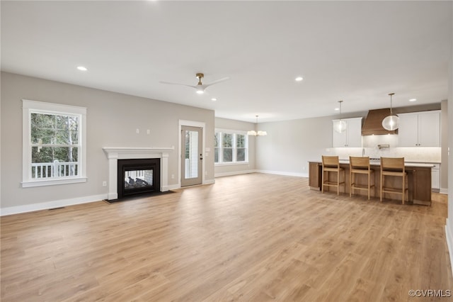 living room with plenty of natural light, light hardwood / wood-style floors, and ceiling fan with notable chandelier