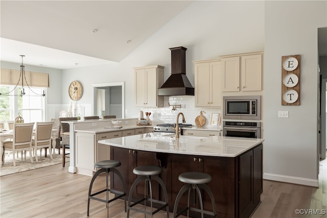 kitchen with a kitchen breakfast bar, a peninsula, an inviting chandelier, stainless steel appliances, and wall chimney exhaust hood