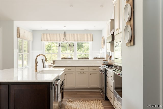 kitchen featuring a peninsula, a sink, dark wood-type flooring, under cabinet range hood, and appliances with stainless steel finishes