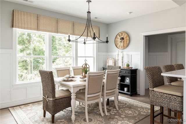 dining space with a chandelier, visible vents, light wood-style flooring, and a wainscoted wall