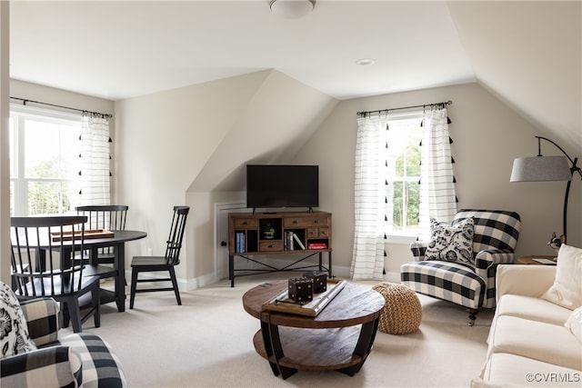 carpeted living room featuring baseboards and lofted ceiling