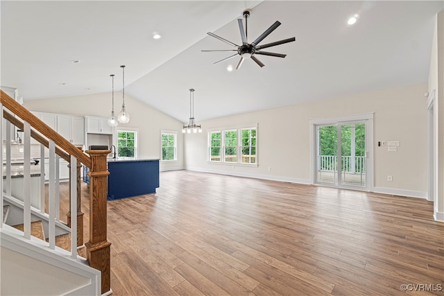 unfurnished living room featuring ceiling fan with notable chandelier, light wood-type flooring, plenty of natural light, and sink