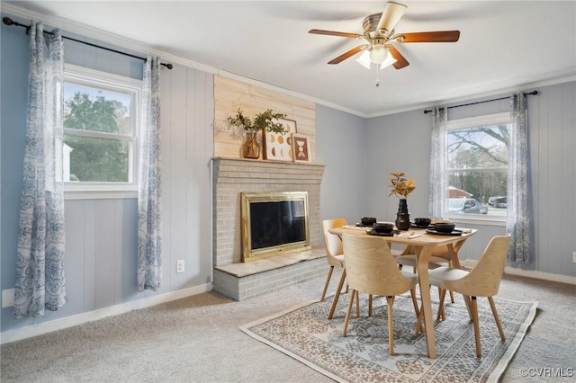 dining space with a brick fireplace, plenty of natural light, ornamental molding, and ceiling fan