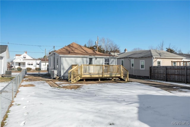 snow covered rear of property featuring central AC unit and a wooden deck