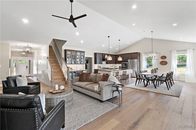 living room featuring ceiling fan, light hardwood / wood-style floors, and lofted ceiling