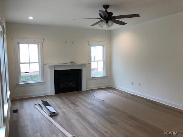 unfurnished living room featuring ceiling fan, a healthy amount of sunlight, and wood-type flooring