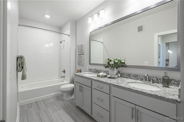 full bathroom with vanity, tiled shower / bath combo, and toilet