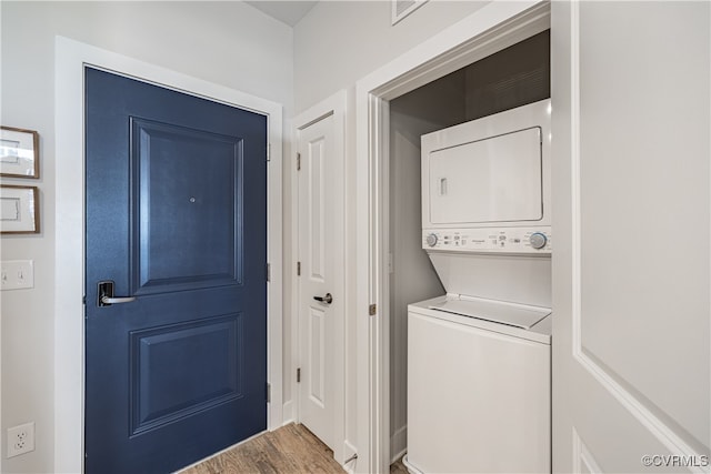 laundry room featuring stacked washing maching and dryer and wood-type flooring