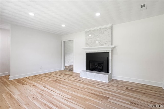 unfurnished living room featuring a premium fireplace and light hardwood / wood-style flooring