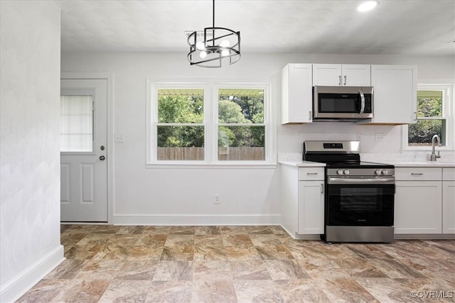 kitchen featuring white cabinets, pendant lighting, stainless steel appliances, and a healthy amount of sunlight