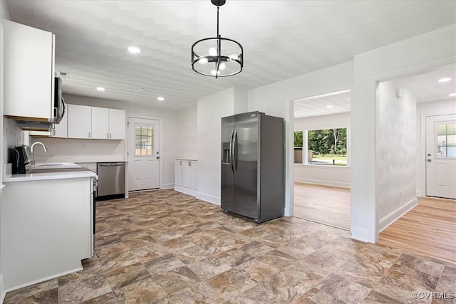 kitchen with a healthy amount of sunlight, pendant lighting, white cabinets, and stainless steel appliances