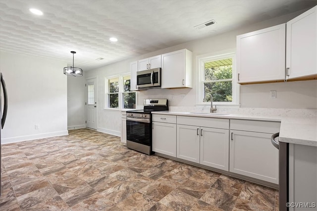 kitchen with pendant lighting, white cabinetry, sink, and appliances with stainless steel finishes