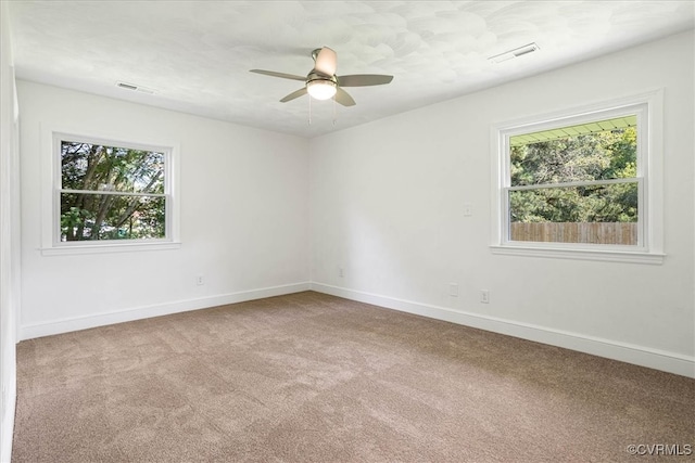 carpeted spare room featuring ceiling fan and a healthy amount of sunlight