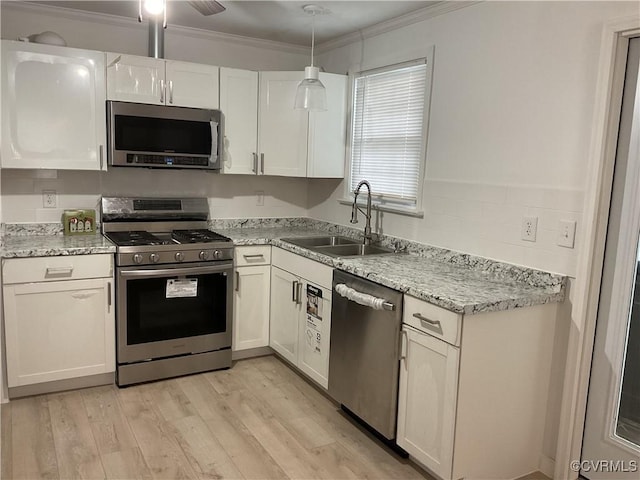 kitchen featuring decorative light fixtures, sink, light wood-type flooring, stainless steel appliances, and white cabinets