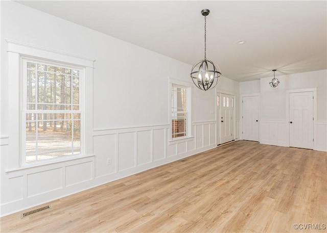 unfurnished dining area featuring a notable chandelier and light wood-type flooring