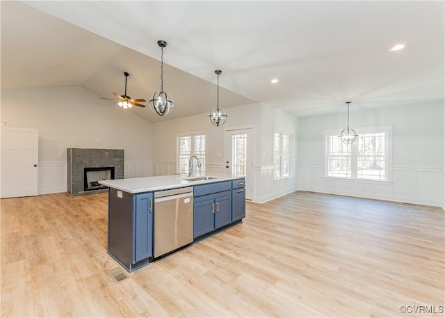 kitchen with blue cabinets, dishwasher, a kitchen island with sink, a high end fireplace, and light hardwood / wood-style flooring