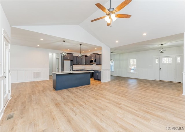 kitchen with sink, light hardwood / wood-style flooring, an island with sink, ceiling fan with notable chandelier, and vaulted ceiling