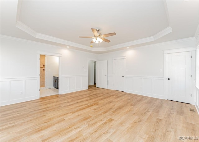 empty room featuring a raised ceiling, ornamental molding, and ceiling fan