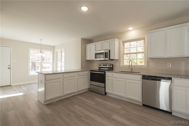 kitchen with sink, light hardwood / wood-style flooring, pendant lighting, white cabinets, and appliances with stainless steel finishes