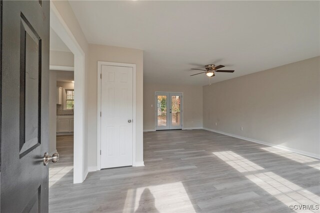 unfurnished living room with ceiling fan, french doors, and light wood-type flooring