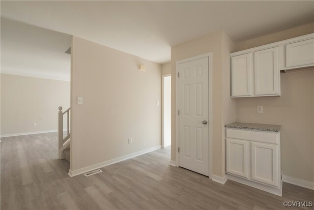 kitchen featuring light stone countertops, white cabinetry, and light hardwood / wood-style floors