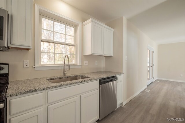 kitchen featuring white cabinetry, light stone countertops, sink, light hardwood / wood-style flooring, and appliances with stainless steel finishes