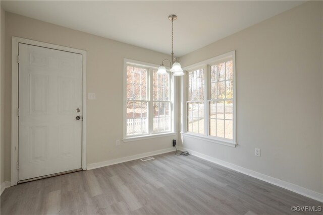 unfurnished dining area featuring hardwood / wood-style floors and a chandelier