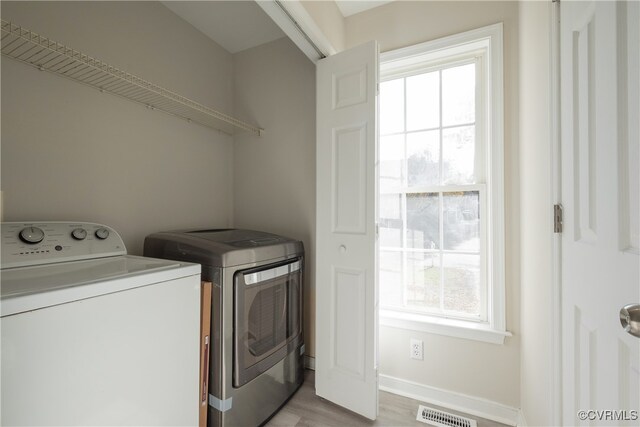 laundry area with washer and clothes dryer, plenty of natural light, and light hardwood / wood-style floors