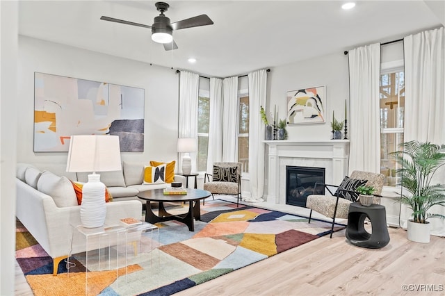 living room with ceiling fan, a healthy amount of sunlight, a high end fireplace, and light hardwood / wood-style floors