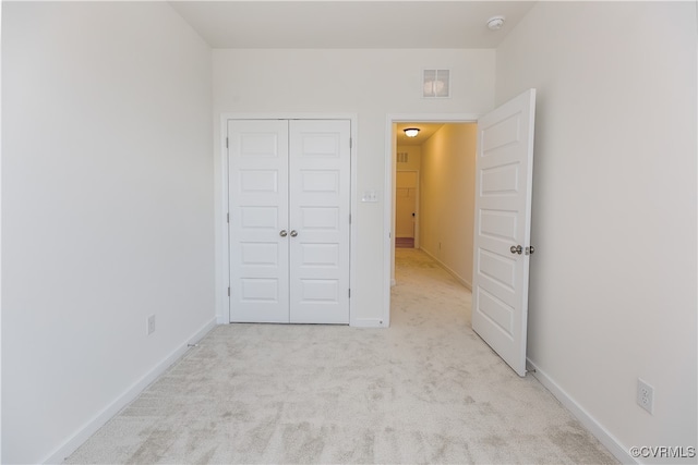 unfurnished bedroom featuring light colored carpet and a closet