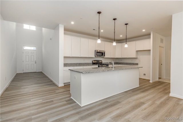 kitchen featuring light wood-type flooring, stainless steel appliances, and a center island with sink