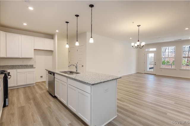 kitchen featuring light stone countertops, pendant lighting, light hardwood / wood-style floors, and a kitchen island with sink