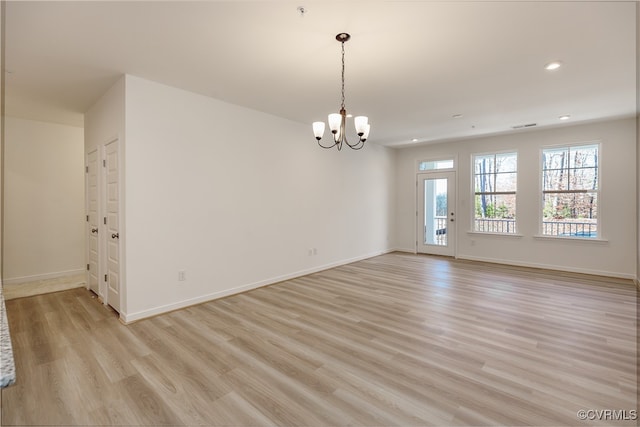 empty room featuring light wood-type flooring and an inviting chandelier