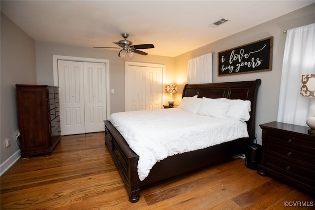 bedroom featuring multiple closets, ceiling fan, and hardwood / wood-style floors