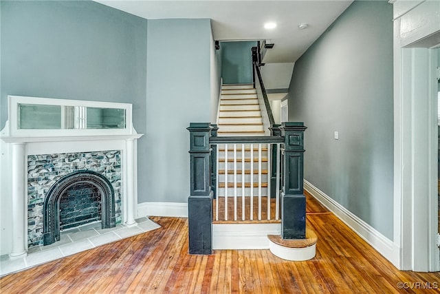 staircase with a tile fireplace and wood-type flooring