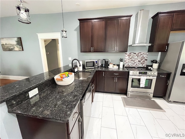 kitchen with sink, wall chimney exhaust hood, hanging light fixtures, dark stone countertops, and appliances with stainless steel finishes