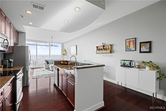 kitchen with stainless steel appliances, dark wood-style flooring, visible vents, floor to ceiling windows, and an island with sink